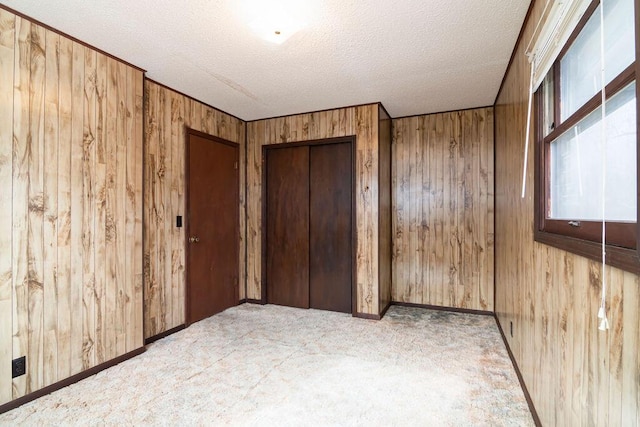 unfurnished bedroom with a closet, wooden walls, and a textured ceiling