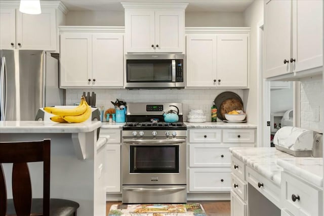 kitchen with backsplash, white cabinets, and stainless steel appliances