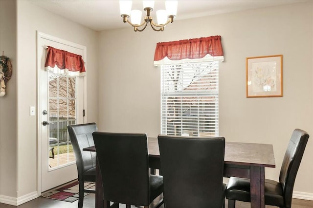 dining area with hardwood / wood-style flooring, a healthy amount of sunlight, and an inviting chandelier