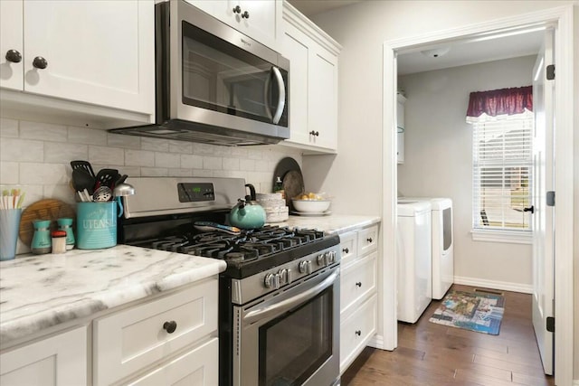 kitchen featuring appliances with stainless steel finishes, white cabinetry, washing machine and clothes dryer, dark hardwood / wood-style floors, and light stone counters