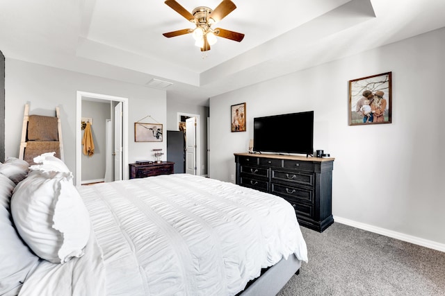 bedroom with a walk in closet, ceiling fan, light colored carpet, and a tray ceiling