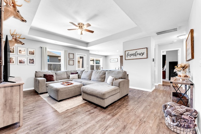 living room featuring ceiling fan, hardwood / wood-style floors, and a raised ceiling