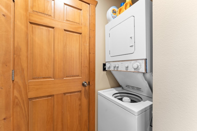 clothes washing area with stacked washing maching and dryer