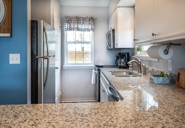 kitchen with sink, stainless steel appliances, white cabinetry, and light stone countertops