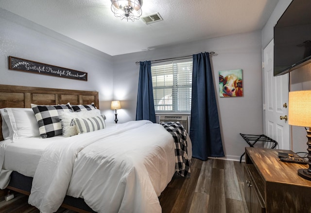 bedroom featuring cooling unit, a textured ceiling, and dark hardwood / wood-style flooring