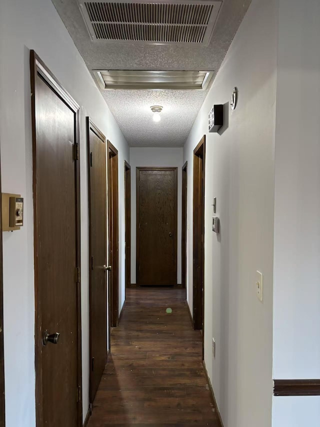 corridor featuring dark wood-type flooring and a textured ceiling