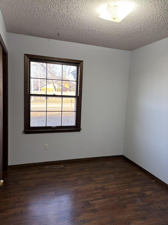 spare room with dark wood-type flooring and a textured ceiling