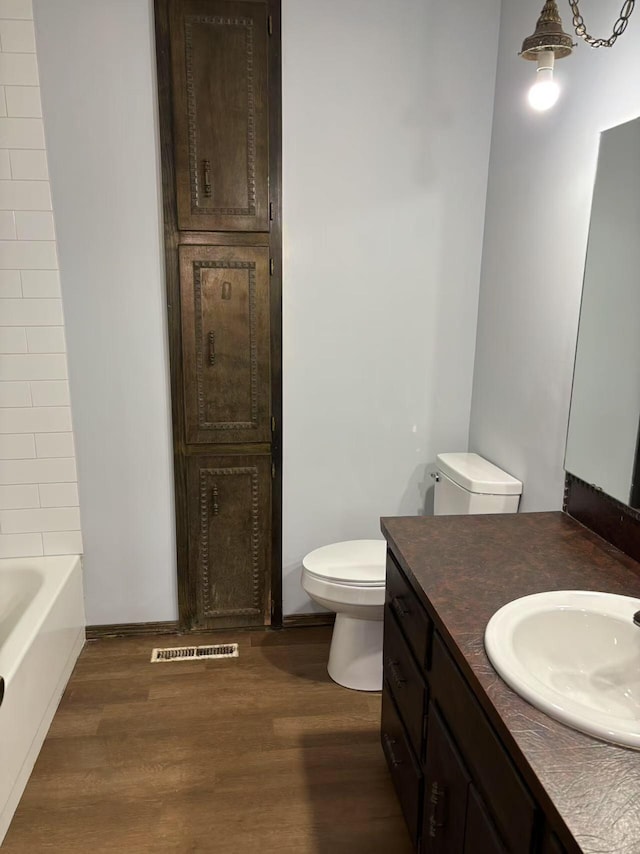 bathroom with vanity, a bathtub, toilet, and wood-type flooring