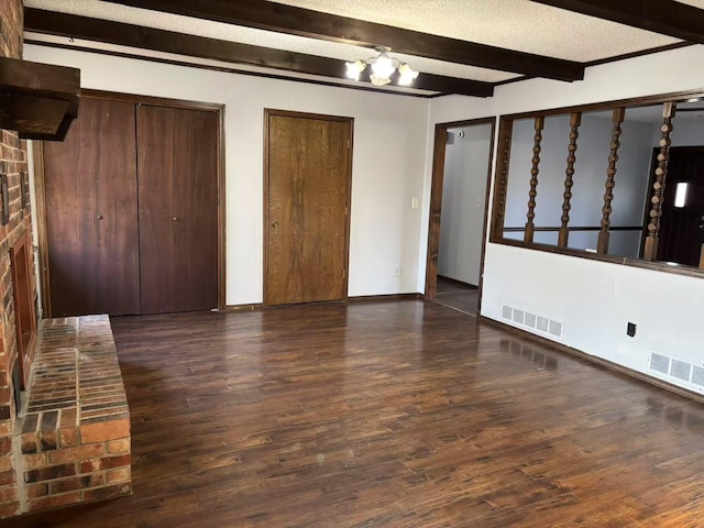 unfurnished bedroom with a notable chandelier, beamed ceiling, a textured ceiling, two closets, and dark wood-type flooring