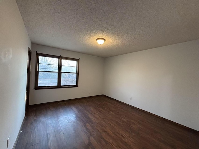 unfurnished room featuring dark wood-type flooring and a textured ceiling