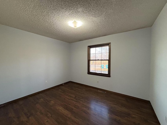 unfurnished room featuring dark wood-type flooring and a textured ceiling