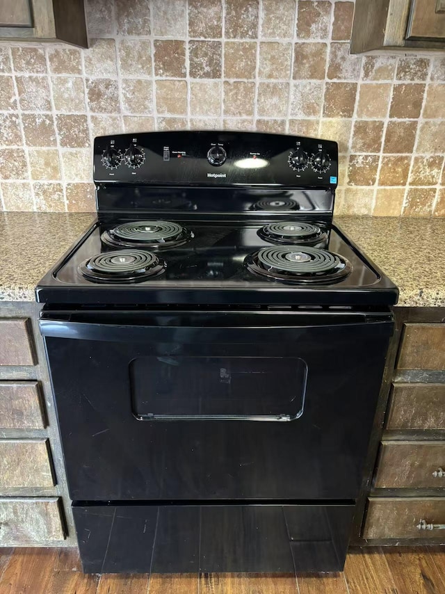 kitchen featuring dark hardwood / wood-style floors, dark brown cabinetry, black range with electric cooktop, and light stone counters