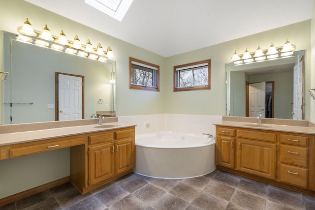 bathroom featuring a bathtub, vanity, and a skylight