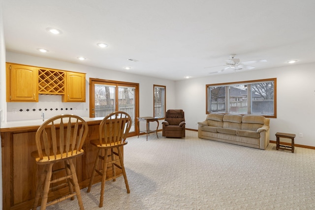 interior space with ceiling fan, bar area, and light carpet