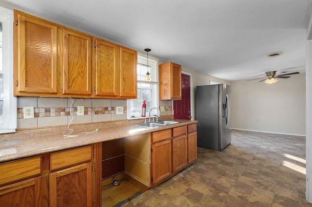 kitchen featuring stainless steel fridge, ceiling fan, hanging light fixtures, sink, and backsplash