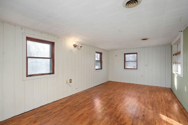 spare room featuring wood-type flooring and wooden walls