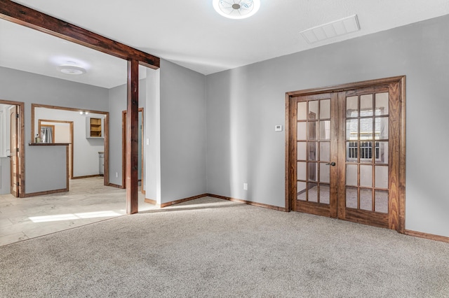 carpeted spare room with beam ceiling and french doors