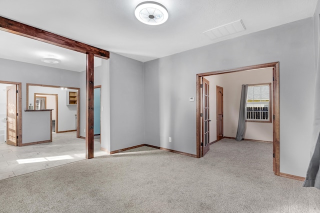 empty room with beam ceiling and light carpet