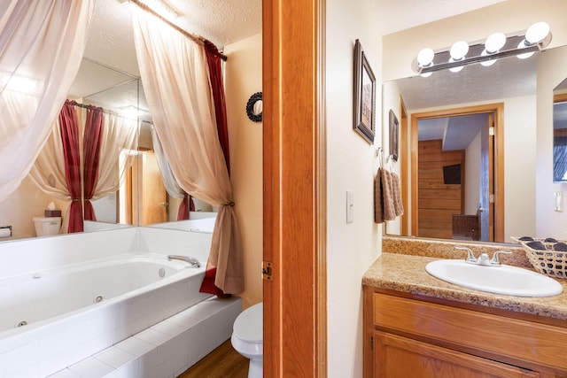 bathroom featuring wood-type flooring, tiled tub, toilet, a textured ceiling, and vanity