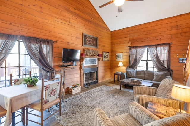 living room featuring wood walls, a healthy amount of sunlight, hardwood / wood-style flooring, and high vaulted ceiling