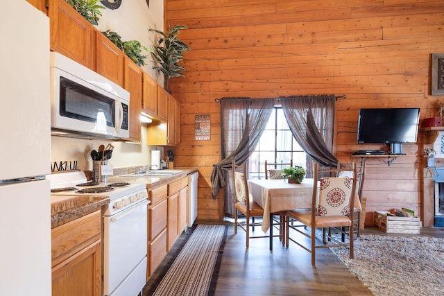 kitchen featuring sink, wood walls, white appliances, and dark hardwood / wood-style floors