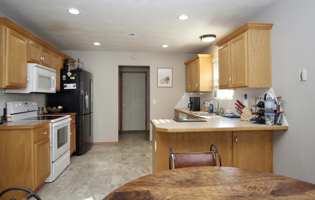 kitchen with kitchen peninsula, sink, tasteful backsplash, white appliances, and a breakfast bar area