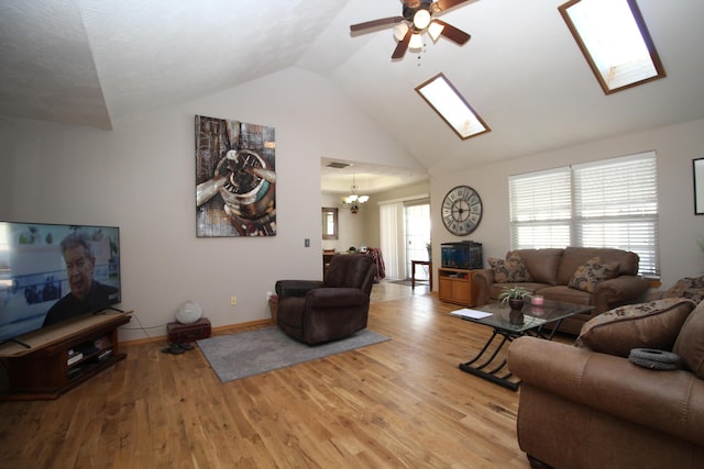 living room with light wood-type flooring, ceiling fan with notable chandelier, and vaulted ceiling with skylight