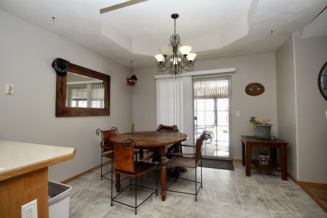 dining area featuring a notable chandelier and a raised ceiling