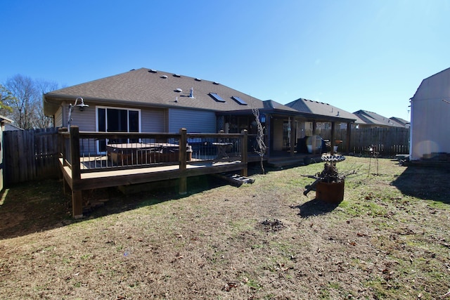 back of house featuring a lawn and a deck