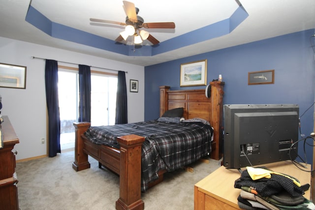 bedroom featuring ceiling fan, light carpet, and a tray ceiling