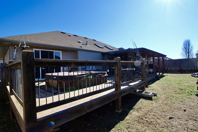 wooden deck with a lawn and a hot tub