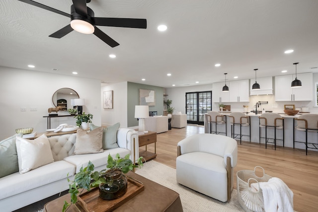 living room with ceiling fan, sink, and light hardwood / wood-style flooring