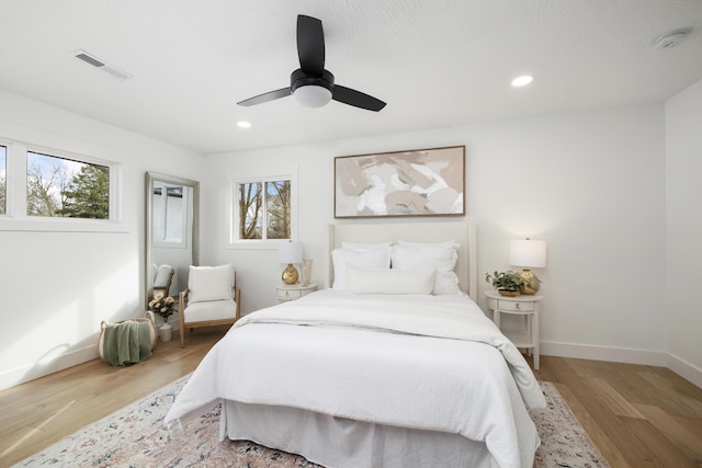 bedroom with multiple windows, light hardwood / wood-style flooring, and ceiling fan