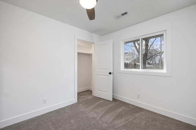 unfurnished bedroom featuring carpet, a closet, ceiling fan, and a walk in closet