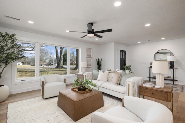 living room featuring ceiling fan, a textured ceiling, and light wood-type flooring