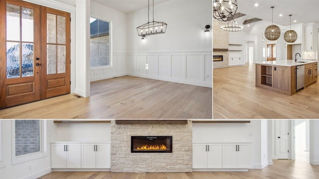 interior space featuring white cabinets, dishwasher, a stone fireplace, sink, and hanging light fixtures