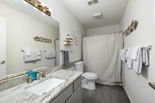 bathroom with a textured ceiling, wood-type flooring, vanity, toilet, and a shower with shower curtain