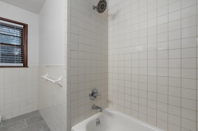 bathroom with tiled shower / bath combo, tile patterned floors, and tile walls