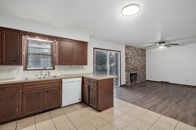 kitchen with dark brown cabinetry, a fireplace, ceiling fan, sink, and white dishwasher