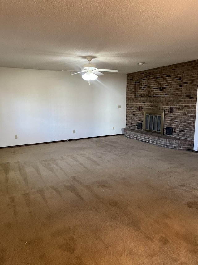 unfurnished living room featuring ceiling fan, a brick fireplace, carpet flooring, and a textured ceiling