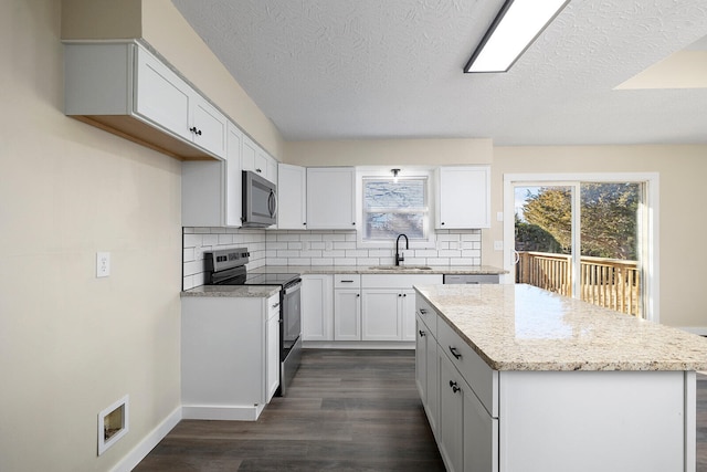 kitchen featuring appliances with stainless steel finishes, sink, backsplash, white cabinets, and a center island