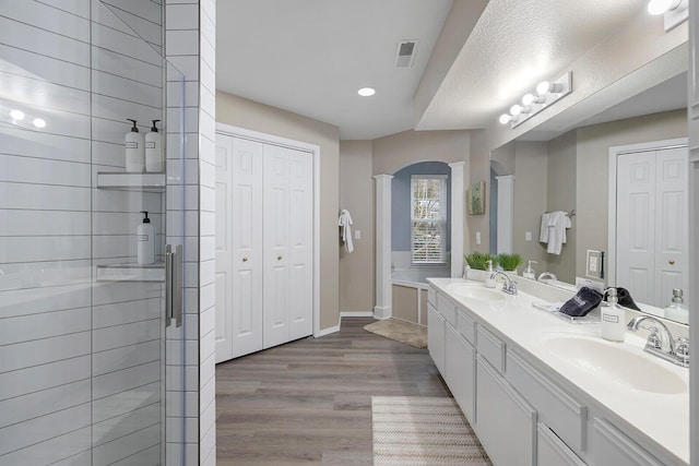 bathroom featuring wood-type flooring, an enclosed shower, a textured ceiling, vanity, and decorative columns