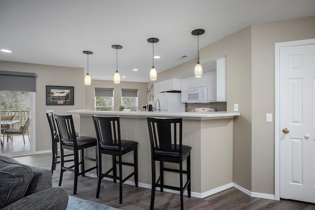 kitchen featuring white cabinetry, white appliances, kitchen peninsula, and a kitchen breakfast bar