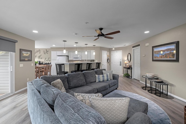 living room with light wood-type flooring and ceiling fan