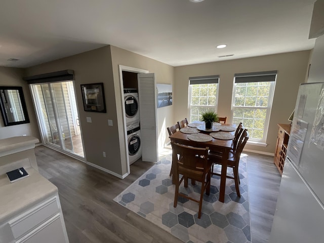 dining room with dark wood-type flooring and stacked washer and dryer