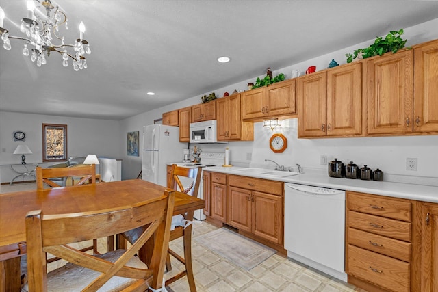 kitchen featuring decorative light fixtures, sink, white appliances, and a notable chandelier