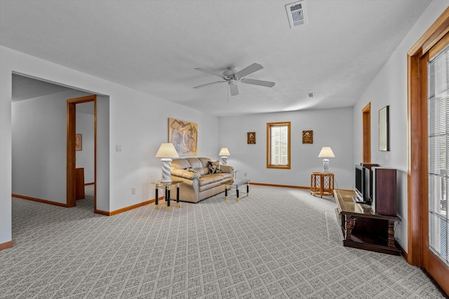 living area featuring light carpet, a textured ceiling, and ceiling fan