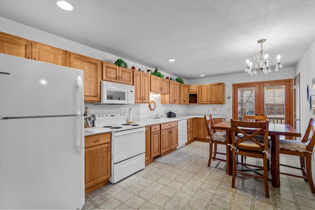 kitchen with hanging light fixtures, french doors, sink, white appliances, and a chandelier