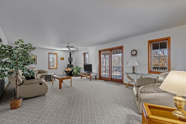 carpeted living room with ceiling fan and a wood stove