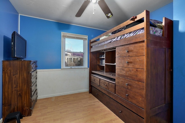 bedroom featuring ceiling fan, wood walls, and light hardwood / wood-style floors